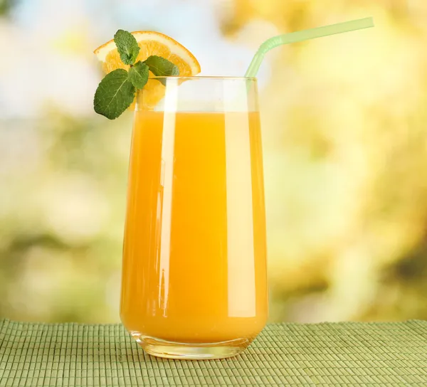 Copo de suco de laranja com hortelã na mesa em fundo brilhante — Fotografia de Stock