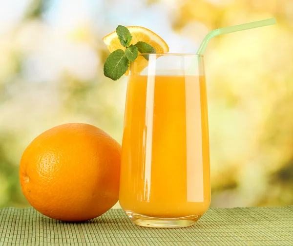 Glass of orange juice with mint and orange on table on bright background — Stock Photo, Image