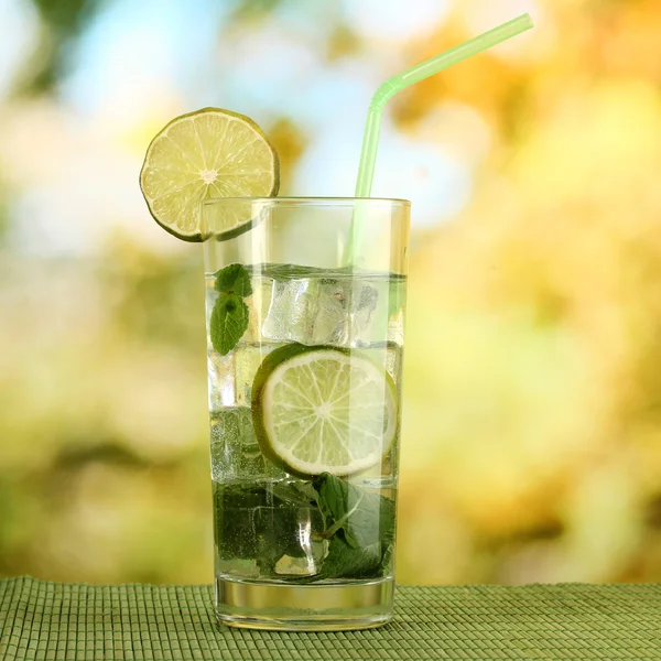 Glass of water with ice, mint and lime on table on bright background — Stock Photo, Image