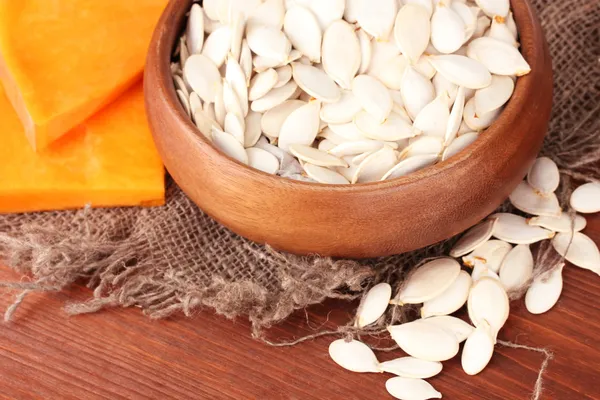 Pumpkin seeds in wooden bowl, on wooden background — Stock Photo, Image