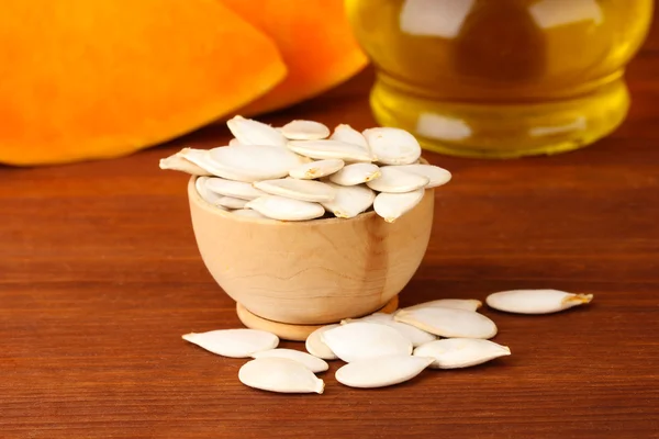 Pumpkin seeds in wooden bowl, on wooden background — Stock Photo, Image