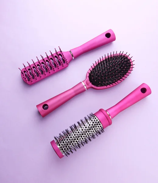 Comb brushes on purple background — Zdjęcie stockowe