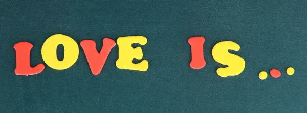 Phrase LOVE IS in colorful letters on school board close-up — Stock Photo, Image