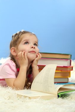 sevimli küçük kız mavi arka plan üzerinde renkli kitaplar