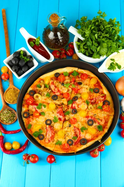 Colorful composition of delicious pizza, vegetables and spices on blue wooden background close-up — Stock Photo, Image