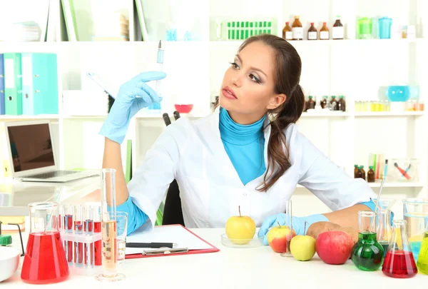 Jonge vrouwelijke wetenschapper injecteren van GGO in appel in laboratorium — Stockfoto