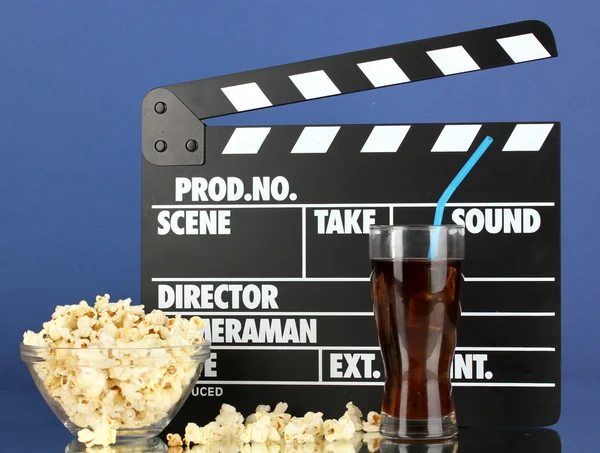 Movie clapperboard, cola and popcorn on blue background — Stock Photo, Image