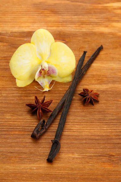 Ο λοβός της βανίλιας και το γλυκάνισο με λουλούδι, για καφέ φόντο ξύλινη — Φωτογραφία Αρχείου