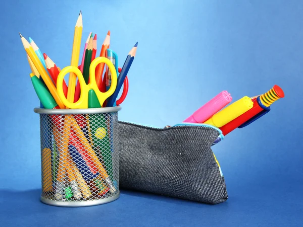 Boîte à crayons avec équipement scolaire sur fond bleu — Photo