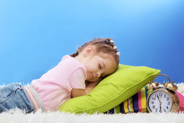 Niedliche kleine Mädchen schlafen auf bunten Kissen, auf blauem Hintergrund — Stockfoto