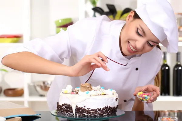 Молодая женщина шеф-повар варить торт на кухне — стоковое фото