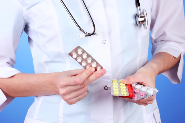 Primer plano de las píldoras de la mano del médico femenino, sobre fondo de color — Foto de Stock