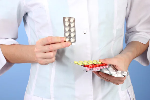Gros plan de femmes médecin mains tenant des pilules, sur fond de couleur — Photo