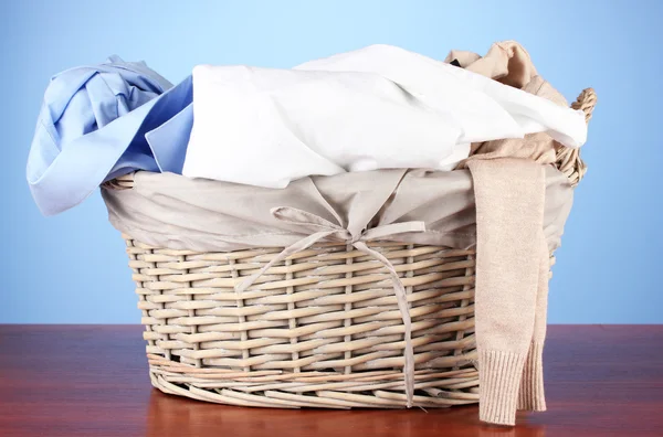 Bright clothes in laundry basket,on color background — Stock Photo, Image