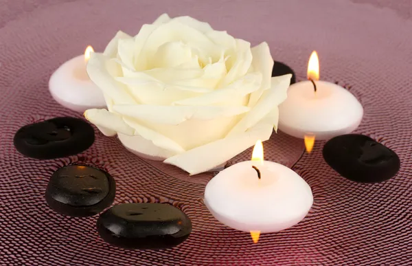 Pietre termali con fiore e candele in acqua sul piatto — Foto Stock