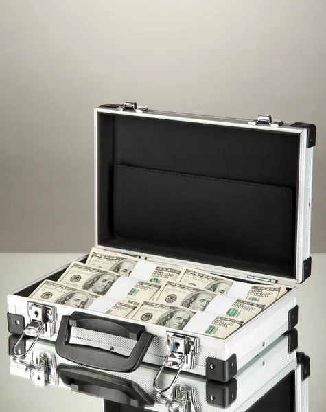 Suitcase with 100 dollar bills on grey background — Stock Photo, Image