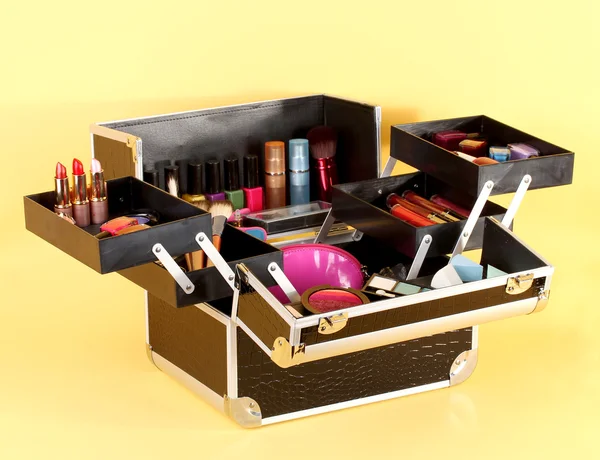 Open case with cosmetics on yellow background — Stock Photo, Image