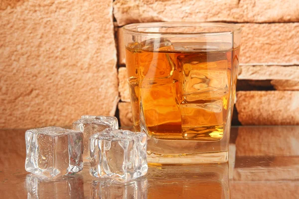 Sklenice whisky a ledu na cihlovou zeď na pozadí — Stock fotografie