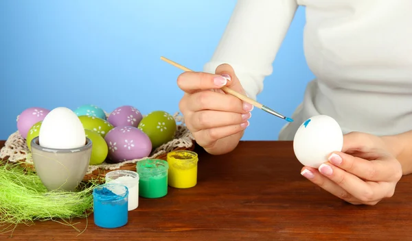 Jovem mulher pintando ovos de Páscoa, no fundo de cor — Fotografia de Stock