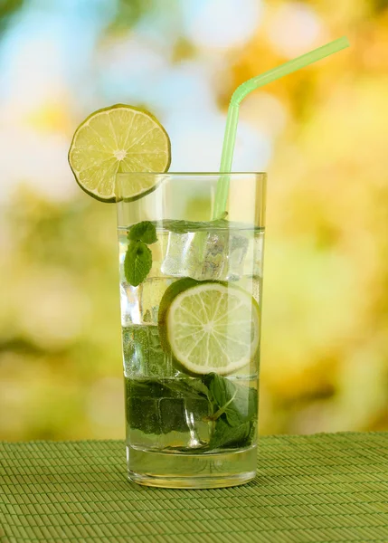 Glass of water with ice, mint and lime on table on bright background — Stock Photo, Image