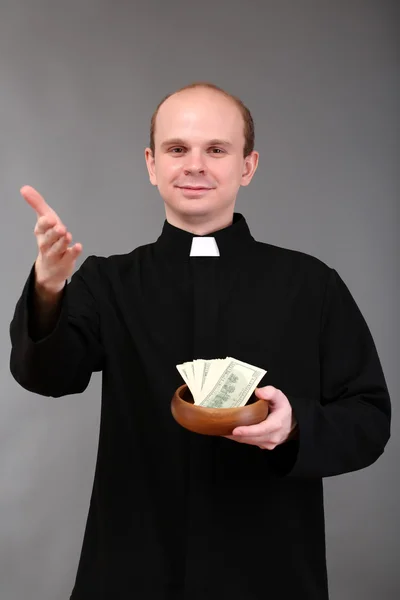 Νεαρό πάστορα με χρήματα σε γκρι φόντο — Φωτογραφία Αρχείου