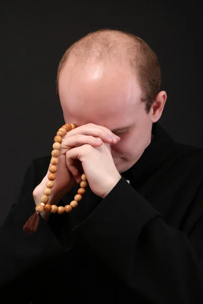 Pendeta muda dengan rosario kayu, terisolasi di atas hitam — Stok Foto