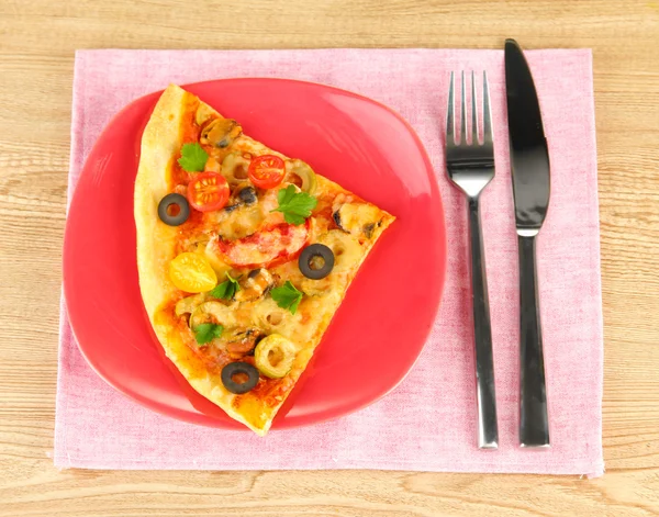 Plate with a slice of delicious pizza on wooden background Stock Image