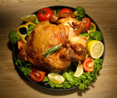 ahşap masa üzerinde plaka üzerinde sebze ile bütün kavrulmuş tavuk