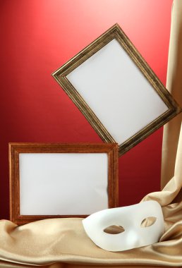 Beyaz maske, boş çerçeveler ve kırmızı zemin üzerine altın ipek kumaş