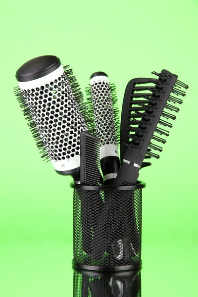 Cesta de ferro com pentes e escovas de cabelo redondas, sobre fundo de cor — Fotografia de Stock