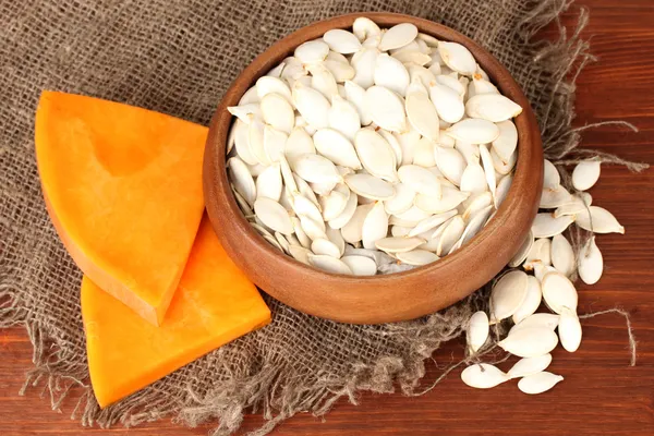 Pumpkin seeds in wooden bowl, on wooden background — Stock Photo, Image