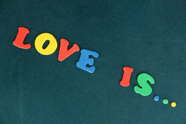 Phrase LOVE IS in colorful letters on school board close-up — Stock Photo, Image