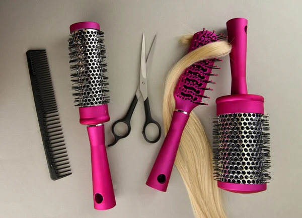 Cepillos para peinar, tijeras para cortar y pelo, sobre fondo gris — Foto de Stock