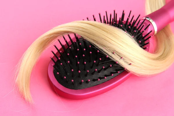 Comb brush with hair, on pink background — Stock Photo, Image