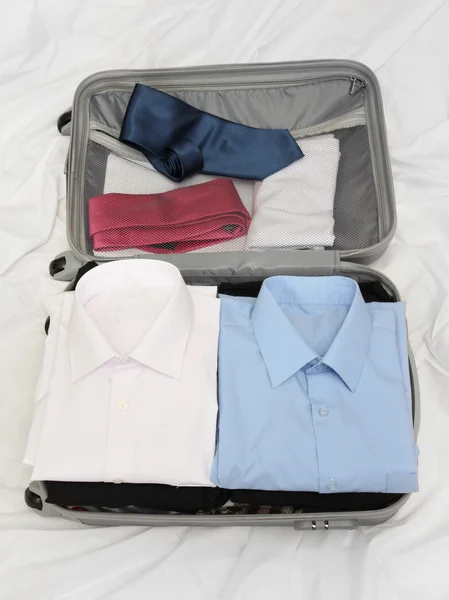 Valise ouverte grise avec vêtements sur le lit — Photo