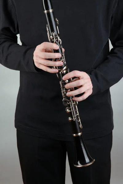 Musicista che suona il clarinetto su sfondo grigio — Foto Stock