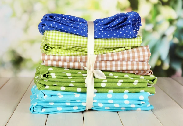 Color mottled fabrics on wooden table on natural background