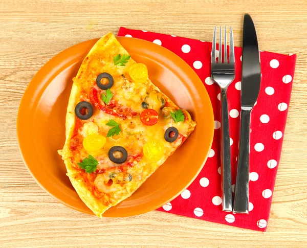 Plate with a slice of delicious pizza on wooden background — Stock Photo, Image