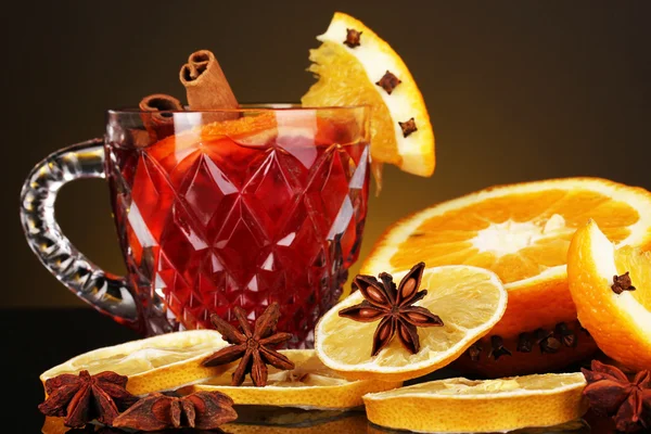 Duftender Glühwein im Glas mit Gewürzen und Orangen auf gelbem Hintergrund — Stockfoto