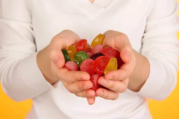 Mains pleines de bonbons sur fond jaune — Photo