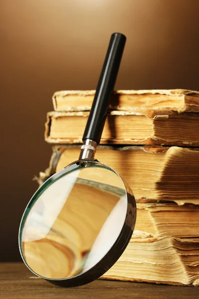 Magnifying glass and books on brown background — Stock Photo, Image