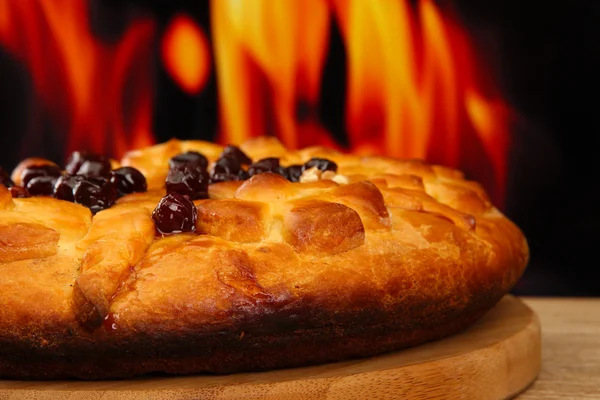 Leckere hausgemachte Torte mit Marmelade, auf Holztisch auf Flammenhintergrund — Stockfoto