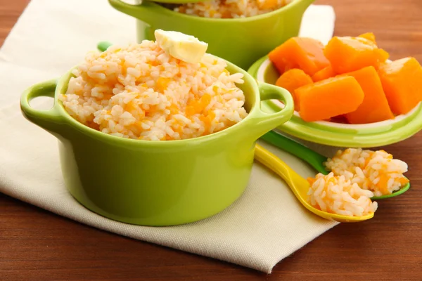 Geschmack Reisbrei mit Kürbis in Töpfen auf hölzernem Hintergrund — Stockfoto