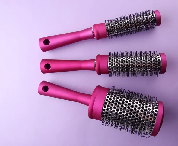 Comb brushes on purple background — Zdjęcie stockowe