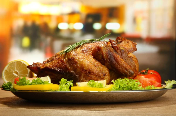 Frango assado inteiro com legumes no prato, na mesa de madeira no café — Fotografia de Stock