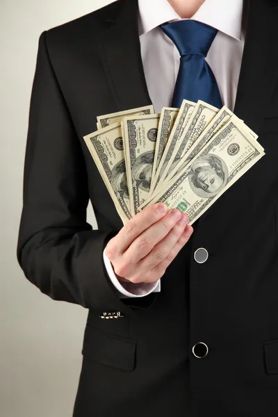 Business man holds lot of money on grey background — Stock Photo, Image
