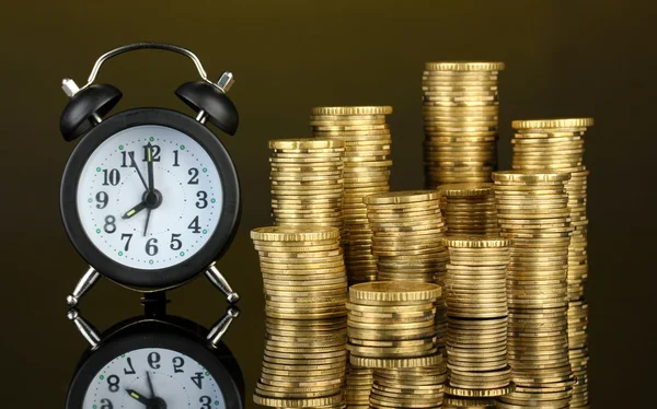 Reloj despertador con monedas sobre fondo oscuro —  Fotos de Stock