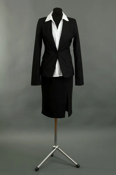 Bílá halenka a černá sukně s kabátem na figurínu na šedém pozadí — Stock fotografie