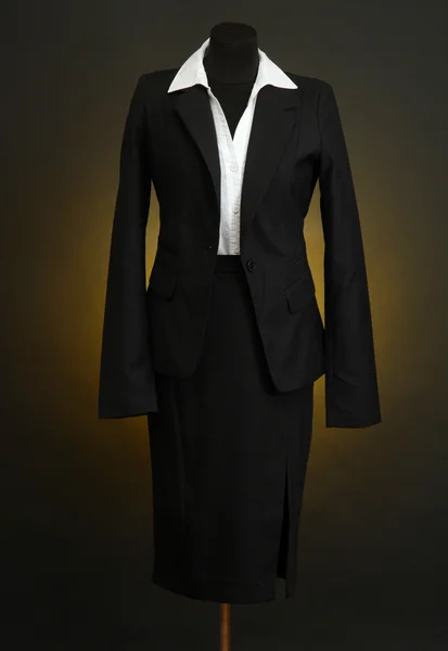 Белая блузка и черная юбка с пальто на манекене на темном фоне — стоковое фото