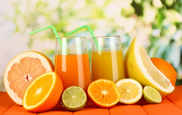 Lots ripe citrus with juices on wooden table on natural background — Stock Photo, Image